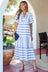 Woman wearing a blue and white striped dress standing outdoors.