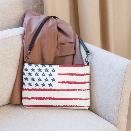 Blue Chico Retail mini leather crossbody purse with American flag design resting on beige couch