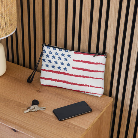 Mini leather crossbody purse with American flag design placed on a wooden surface next to keys and smartphone