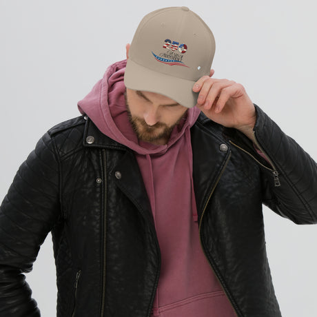 Man wearing a beige united states of america hat with an embroidered design paired with a black leather jacket and maroon hoodie